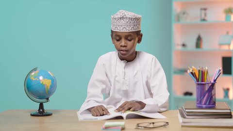 الاستعانة بمجسم الكرة الأرضية في الدراسة, تحديد موقع الدول والبلدان العربية على خريطة العالم, بورتريه لصبي عربي خليجي عماني مبتسم يرتدي الدشداشة والكمة يقوم بالمذاكرة, خلفية زرقاء