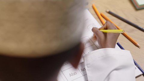 القيام بالمهام التعليمية الفعالة, اكتساب المعرفة من كتابة الواجبات، بورتريه من الخلف لتلميذ عربي خليجي عماني يرتدي الدشداشه والكمة مندمج في الدراسة