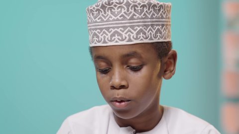 الاستمتاع بقراءة الكتب، موسم العودة للمدارس، إنجاز الواجبات اليومية، تلميذ عربي خليجي عماني يرتدي الدشداشه والكمه مندمج في القراءة, ثقافة التعلم الذاتي, خلفية زرقاء