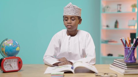 مفهوم تنظيم و إدارة الوقت, أهمية الراحة والنوم الجيد في تعزيز الصحة العقلية والجسدية للطلاب، طالب عربي خليجي عماني يرتدي الدشداشة والكمة نائم على الطاولة بعد الدراسة, خلفية زرقاء