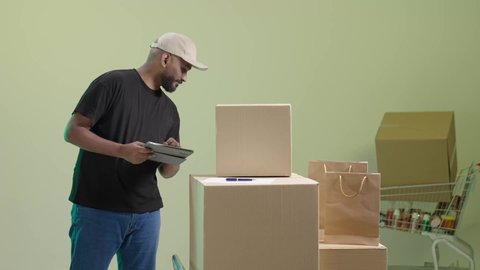 التسوق و شراء الحاجيات عن طريق الانترنت، خدمة التوصيل السريع والآمن في السعودية، تسجيل الطلبات من جهاز التابلت، بورتريه لمندوب عربي خليجي سعودي يرتدي الزي الكاجوال و قبعة بيج يحمل الجهاز اللوحي و يباشر عمله, الاستفادة من التكنولوجيا الحديثة بتسهيل العمل، خلفية خضراء