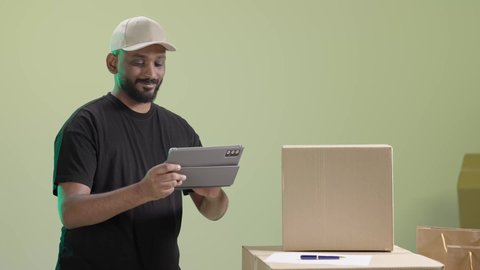 تسجيل الطلبات من جهاز التابلت، بورتريه لمندوب عربي خليجي سعودي يرتدي الزي الكاجوال و قبعة بيج  يحمل الجهاز اللوحي و يباشر عمله, الاستفادة من التكنولوجيا الحديثة بتسهيل العمل، خلفية خضراء