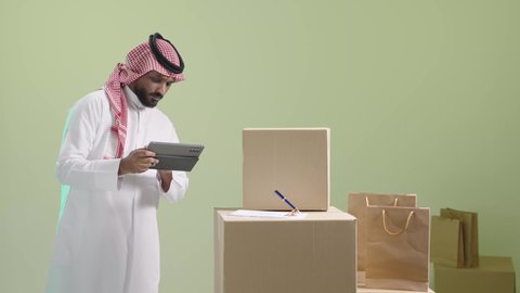 الالتزام بالجدول الزمني المكتوب لضمان وصول الطلبية بالوقت المحدد، مراجعة بيانات العملاء من خلال التابلت, بورتريه لمندوب عربي خليجي سعودي يرتدي الزي التقليدي والشماغ يحمل الجهاز اللوحي و يباشر عمله, خلفية خضراء