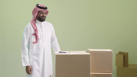 إعداد كشف الشحنات اليومية للمندوبين, مفهوم التسوق الالكتروني, الطلبات الاونلاين والتسوق الذكي, عملية شحن و توصيل موثوقه, بورتريه لمندوب عربي خليجي سعودي يرتدي الزي التقليدي والشماغ يقوم بتدوين الطلب, خلفية خضراء