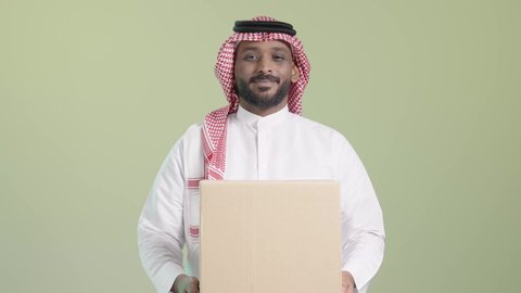 شركة شحن و توصيل البضائع, تسليم الطلبات في الوقت المحدد و بشكل سليم، التسوق و طلب المنتجات عبر الإنترنت، بورتريه لمندوب عربي خليجي سعودي يرتدي الزي التقليدي و الشماغ يحمل صندوق كرتوني و يسلمه بابتسامة, ايماءات السعادة و السرور, خلفية خضراء