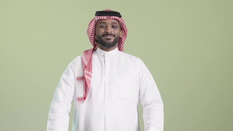 طلب وإستلام الدليفري, بورتريه لمندوب عربي خليجي سعودي يرتدي الزي التقليدي و الشماغ يحمل أكياس و يسلمها بابتسامة, ايماءات السعادة و السرور, خلفية خضراء