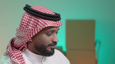 الاندماج والتركيز في العمل, بورتريه لرجل عربي خليجي سعودي يرتدي الثوب التقليدي والشماغ,  خلفيه ضبابيه لصناديق كرتون ، عملية شحن وتوصيل موثوقه ، ايماءات الرضا والسرور بالخدمه