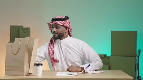 أوراق و مستندات استلام و تسليم الطرد, كتابة و تسجيل بيانات الشحنة، خدمة الشحن و التوصيل ذات الجودة العالية، بورتريه لرجل عربي خليجي سعودي يرتدي الزي التقليدي والشماغ يقوم بمراجعة الطلب, خلفية ملونة