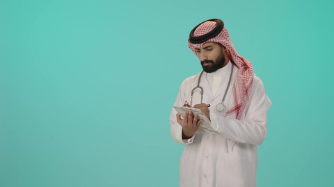 تدوين وتسجيل معلومات وملفات المرضى, مفهوم الرعاية الصحية في السعودية، بورتريه لطبيب عربي خليجي سعودي  يرتدي الثوب التقليدي والشماغ مع المعطف الأبيض يضع سماعة الفحص و يقوم بالكتابة على ملف, تقديم الخدمات العلاجية في المراكز الطبية والمستشفيات, خلفية زرقاء