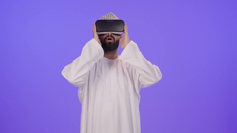 إيماءات الاندماج ومحاكاة العالم الخيالي، التطور التقني والتكنولوجي، المتعة بالمشاهدة عبر نظارة الواقع الافتراضي, بورتريه لشاب عربي خليجي عماني يرتدي الدشداشة والكمة  ينظر من خلال نظارات ثلاثية الأبعاد (الفي ار)، خلفية بنفسجية
