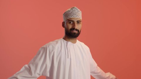 التعبير عن الحب وتقديم الولاء للراية العمانية، الفخر والاعتزاز بالانتماء لسلطنة عمان، بورتريه لرجل عربي خليجي عماني يرتدي الدشداشة والكمه يلف العلم العماني على كتفيه وينظر إلى الكاميرا بإيماءات السعادة والسرور، خلفية برتقالي