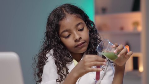 إجراء أبحاث وتجارب داخل المختبر، تصوير لبنت عربية خليجية سعودية سمراء ترتدي المعطف الطبي الأبيض تقوم بإجراء تحاليل طبية كيميائية بأنابيب إختبار التفاعلات الكيميائية ،اجراء التحاليل الطبية ، المختبر الطبي و معمل الكيمياء ، مفهوم مهن مستقبلية ، ايماءات الاندماج و التركيز