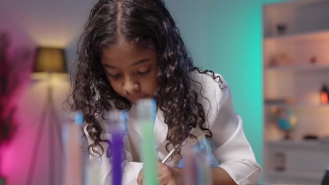The concept of future professions, experiments and scientific laboratory research, a close-up shot of a Saudi Arabian Gulf girl with a dark complexion sitting at a desk wearing a white lab coat, recording the results of medical examinations, conducting medical analyses, a chemistry lab and laboratory, white background.