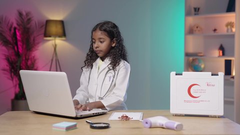 مهن ووظائف مستقبلية، العمل في المجال الطبي، إستخدام أجهزة تقنية حديثة، حقيبة الإسعافات الأولية،  تصويرمقرب لبنت عربية خليجية سعودية سمراء ترتدي المعطف الطبي و السماعات الخاص بمهنة الطبيب تقوم بإدخال البيانات الطبية في جهاز الحاسوب المحمول