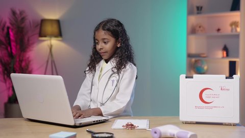 إستخدام أجهزة تقنية حديثة ،العمل في المجال الطبي، حقيبة الإسعافات الأولية،  تصويرمقرب لبنت عربية خليجية سعودية سمراء ترتدي المعطف الطبي و السماعات الخاص بمهنة الطبيب ،  تقوم بإدخال البيانات الطبية في جهاز الحاسوب المحمول ، مهن ووظائف مستقبلية