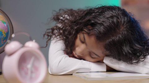 التعب والاجهاد أثناء المذاكرة, أهمية الراحة والنوم الجيد في تعزيز الصحة العقلية والجسدية للطلاب، تصوير لبنت عربية سعودية خليجية سمراء ترتدي الزي المدرسي  تأخذ قيلولة أثناء مذاكرتها للدروس، الدراسة لساعات متأخرة في الليل