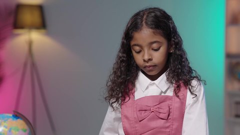 أهمية التعليم في بناء مستقبل مشرق للمجتمع، بورتريه مقرب لبنت عربية خليجية سعودية سمراء ترتدي الزي المدرسي تقوم بالنظر الى الاسفل، ايماءات الاندماج و التركيز