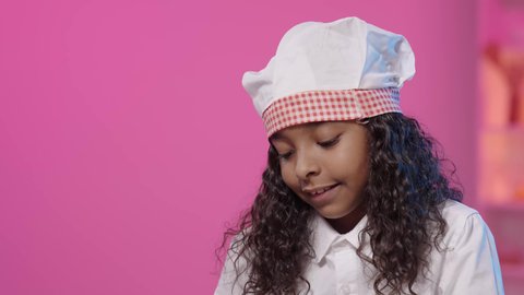 الطهي الاحترافي وفنون تقديم الأطباق، ايماءات الاندماج و التركيز، تصويرمقرب لفتاه عربية خليجية سعودية سمراء ترتدي زي الشيف الخاص تنظر الى الاسفل ، مهن و وظائف مستقبلية