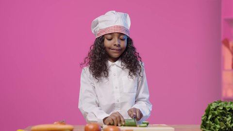 مهارات الطهي وفنون إعداد الطعام، تصوير لفتاه عربية خليجية سعودية سمراء ترتدي زي الشيف الخاص  تقوم بتقطيع الخضراوات بسعادة على الطاولة ، مشاركة تحضير الوصفات على مواقع التواصل الاجتماعي ، مهن و وظائف مستقبلية