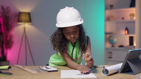 أدوات و معدات هندسية، تصوير لبنت عربية خليجية سعودية سمراء ترتدي خوذة و سترة حماية خاصة بالعمل الهندسي  ترسم بالفرجار الهندسي على مخطط تصميم هندسي  ، مهن ووظائف هندسية