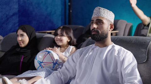 توطيد العلاقة الأسرية، مشاهدة فيلم سينمائي داخل قاعة السينما، قضاء أوقات ممتعة ومسلية، الاستمتاع بمشاهدة المباريات في عطلة نهاية الأسبوع، عائلة عربية خليجية عمانية أم ترتدي الحجاب والعباءة تجلس في السينما مع زوجها وطفلتها، نزهات الأصدقاء لقضاء أوقات ممتعة