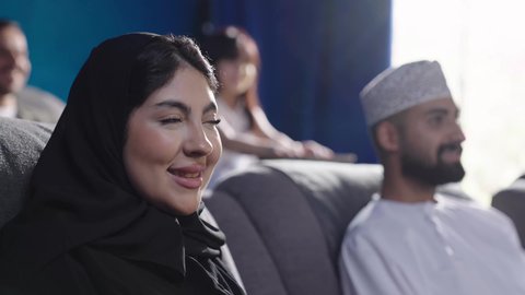 مشاهدة فيلم سينمائي داخل قاعة السينما، قضاء أوقات ممتعة ومسلية، الاستمتاع بمشاهدة المباريات في عطلة نهاية الأسبوع، بناء علاقات اجتماعية ناجحة، تصوير مقرب إمرأة عربية خليجية عمانية ترتدي الحجاب والعباءة تجلس في السينما، نزهات الأصدقاء معا لقضاء أوقات ممتعة