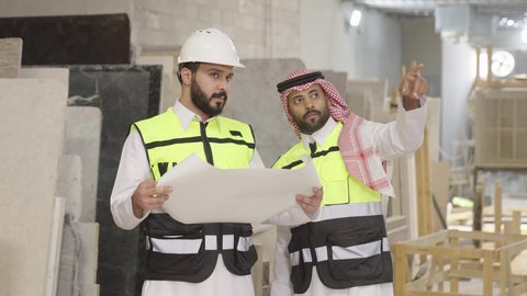 حوارات ونقاشات هادفة، تصوير لمهندس عربي خليجي سعودي يرتدي سترة وخوذة الحماية يحمل مخطط هندسي برفقة زميله، الاشراف على سير خطة العمل، معامل ومصانع  محليه سعوديه، الإشراف على العمليات الصناعية اليومية