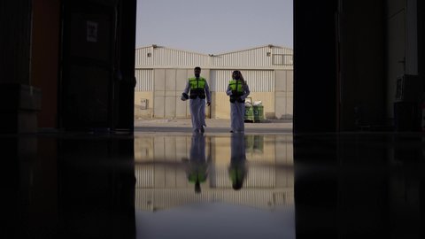 معامل ومصانع  محليه سعوديه، ارتداء خوذة الحمايه في المصنع، تصوير ظلي لمهندسان عربيان سعوديان خليجيان يرتديان الثوب يقومان بالمشي  في احدى المستودعات