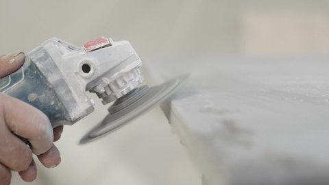 Cutting and processing natural marble, crafts and industrial manual work, close-up of a Saudi Gulf Arab worker using a synthetic marble saw inside the factory, operating industrial equipment.