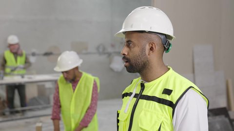 الاشراف على سير خطة العمل، تبادل وجهات النظر في حوارات هادفة، مصنع تصنيع الرخام، تصوير لمهندس عربي خليجي عماني يرتدي سترة وخوذة الحماية يحمل مخطط هندسي برفقة زميله، حرف ومهن يدوية شعبية