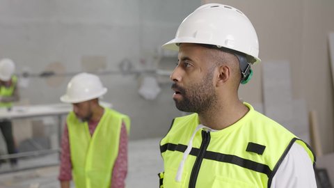 تبادل وجهات النظر في حوارات هادفة، مصنع تصنيع الرخام، تصوير لمهندس عربي خليجي عماني يرتدي سترة وخوذة الحماية يحمل مخطط هندسي برفقة زميله ، الاشراف على سير خطة العمل، حرف ومهن يدوية شعبية