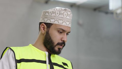 Meaningful dialogues and discussions, marble manufacturing factory, close-up shot of an Arab Gulf Omani engineer wearing a safety vest and helmet supervising the progress of the work plan, popular crafts and manual professions.