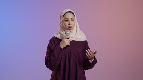 عقد ندوات تعليمية وإلقاء المحاضرات، بورتريه لامراة عربية خليجية سعودية محجبه ترتدي العباءة تحمل بيدها الميكروفون ، العمل في تقديم الفقرات و البرامج الفنية, خلفية ملونه