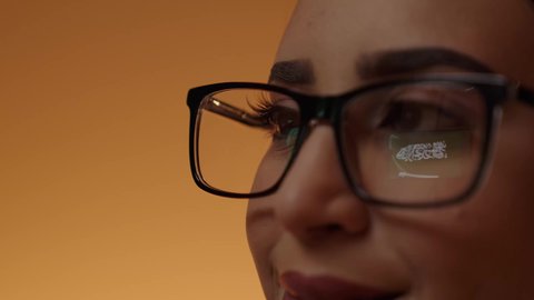 A close-up shot of the eye of a smiling Saudi Arabian Gulf girl wearing glasses, looking proudly at the flag of the Kingdom, with the reflection of the Saudi flag on the lens of her eye, commemorating Saudi National Day on September 23, the day of the establishment of the first Saudi state in 1727 AD.