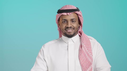 الاهتمام بالمظهر الخارجي، مفهوم الاناقه والرجولة، بورتريه مقرب لرجل عربي خليجي سعودي مبتسم يرتدي الشماغ و الثوب التقليدي يقف بأيدي متقاطعه ينظر إلى الكاميرا بتعابير الثقة بالنفس ,خلفية خضراء