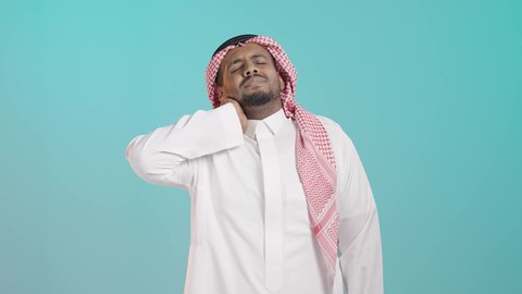 ضرورة الاسترخاء وأخذ قسط من الراحة،، التهاب المفاصل والعضلات في الرقبة، آلام العظام والعمود الفقري، الحاجة للذهاب إلى الطبيب والمعاينة، بورتريه  لرجل عربي خليجي سعودي يرتدي الثوب التقليدي و الشماغ يضع يده حول عنقه بإيماءات التألم، خلفية خضراء
