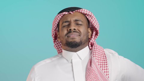 Back pain and spine, a portrait of a Saudi Arabian Gulf man wearing a white thobe and a ghutrah, placing his hand on his back, facial and hand gestures indicating pain and discomfort, fatigue and exhaustion, and a sense of illness, the need for treatment, green background.