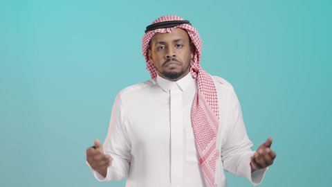 التردد وعدم الثقة بخصوص أمر معين، بورتريه مقرب لرجل عربي خليجي سعودي يرتدي الثوب الابيض و الشماغ  ينظر إلى الكاميرا يرفع يديه يفتح كفيه بإيماءات عدم التأكد, الشعور بالقلق وعدم المعرفة، الحيرة باتخاذ القرار الصحيح، خلفية خضراء
