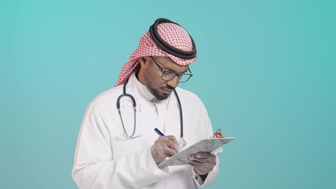 الاهتمام بالمرضى وتسجيل الملاحظات الطبيه، تدوين الحالات المرضية والمتابعه ، بورترية لطبيب عربي خليجي سعودي يرتدي المعطف و السماعة الطبية يقوم بكتابة تقرير طبي ، العمل في القطاع الصحي في المملكة العربية السعودية , خلفية خضراء