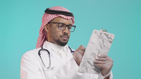 الاهتمام بالمرضى وتسجيل الملاحظات الطبيه، تدوين الحالات المرضية ومتابعه المرضى، بورترية لطبيب عربي خليجي سعودي يرتدي المعطف و السماعة الطبية يقوم بكتابة تقرير طبي ، العمل في القطاع الصحي في المملكة العربية السعودية , خلفية خضراء