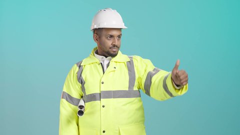 الاشارة الى شيء ما ، مفهوم القبول والموافقه، تعابير الإعجاب والرضى ، بورترية لمهندس عربي خليجي سعودي يرتدي ستره و خوذه الحماية يحمل المخطط الهندسي ، الاشراف على المشاريع المعمارية بشكل مباشر، خلفية خضراء