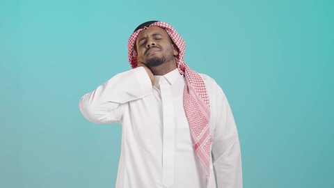 Neck, bone, and spine pain, facial gestures indicating distress and pain, the necessity to see a doctor and receive treatment, a portrait of a Saudi Arabian Gulf man wearing a white thobe and a ghutrah holding his neck with expressions of pain, muscle and joint inflammation, green background.