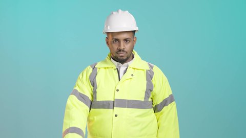 مفهوم الهندسة والانشاءات المعمارية، طلب التوقف وعدم الاقتراب، الرفض والامتناع والانزعاج، العمل في القطاع الهندسي، بورتريه لمهندس عربي خليجي سعودي يرتدي سترة الحماية و الخوذة يمد يرفع كفه نحو الأمام بإيماءات النهي, خلفية خضراء