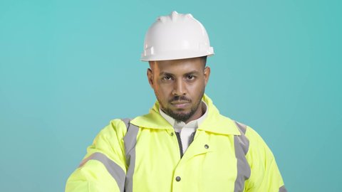 الرفض والامتناع والانزعاج, طلب التوقف وعدم الاقتراب, مفهوم الهندسة والانشاءات المعمارية، العمل في القطاع الهندسي، بورتريه لمهندس عربي خليجي سعودي يرتدي سترة الحماية و الخوذة يمد يرفع كفه نحو الأمام بإيماءات النهي, خلفية خضراء