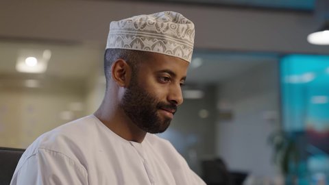 الشركات والمكاتب في سلطنة عمان, أجواء عمل وإنجاز مهام، مفهوم إدارة شؤون الأعمال وتنظيمها, رجل عربي خليجي عماني يرتدي الدشداشة و الكمة,  توفير بيئة عمل مريحة ومناسبة