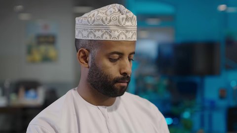 عرض شاشة الجوال, تصفح مواقع التواصل الاجتماعي عبر الانترنت، استخدام الهاتف المحمول في العمل، رجل عربي خليجي عماني مبتسم يرتدي الدشداشة و الكمة يعمل من خلال الموبايل, الاستفادة من الأجهزة التكنولوجية الحديثة والمتطورة