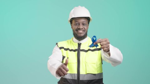 المهارة و اتقان العمل، رفع اصبع الابهام لاعلى بتعابير الرضا والاعجاب, العمل في القطاع الهندسي، بورتريه لمهندس أسمر عربي خليجي سعودي مبتسم يرتدي الخوذه و سترة الحماية و يمسك شريط أزرق دلالة على الجودة العالية يرفع الابهام للأعلى باشارة اللايك، مهن ووظائف سعودية، خلفية زرقاء