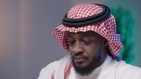 مفهوم التمعن والتركيز, اكتساب المعرفة والخبرة بإيماءات الدقة، الدراسات والتجارب في بيئة عملية متطورة، بورتريه لرجل أسمر عربي خليجي سعودي يرتدي الثوب التقليدي و الشماغ و المعطف الطبي مندمج في العمل