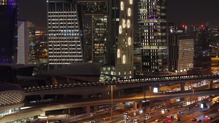 حركة مرور السيارات في الشوارع العامة ليلا، الفن الهندسي المعماري للأبراج وناطحات السحاب، شبكة المواصلات والسكك الحديدية بالعاصمة، وسائل التنقل الحديثة، خط قطار مترو الرياض امام مركز الملك عبدالله المالي (كافد)، معالم سياحية مشهورة في المملكة العربية السعودية