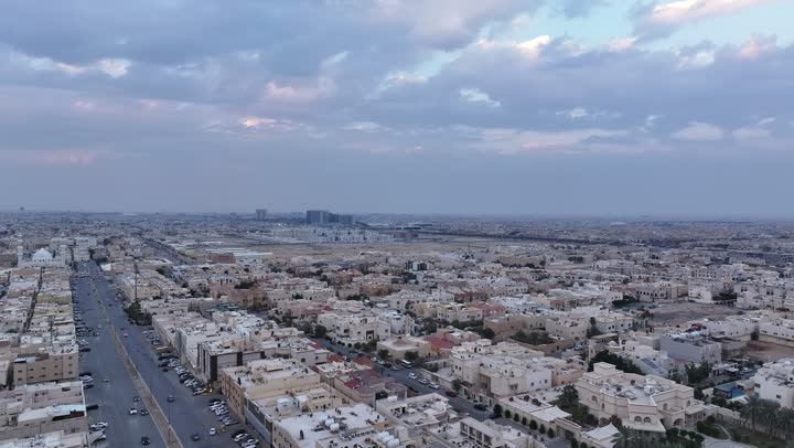 The growth, development and urban progress of commercial buildings and facilities, the architectural art of towers and skyscrapers, aerial drone photography of Riyadh at sunset, the economic and urban renaissance of the capital's skyline